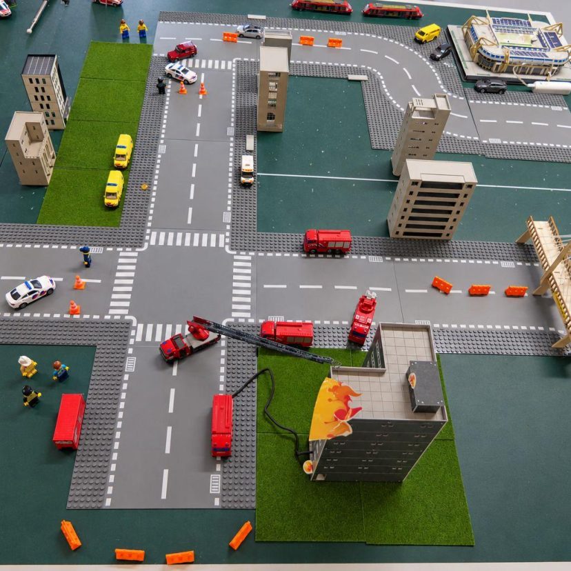 Een maquette van een stad met (hulp)voertuigen